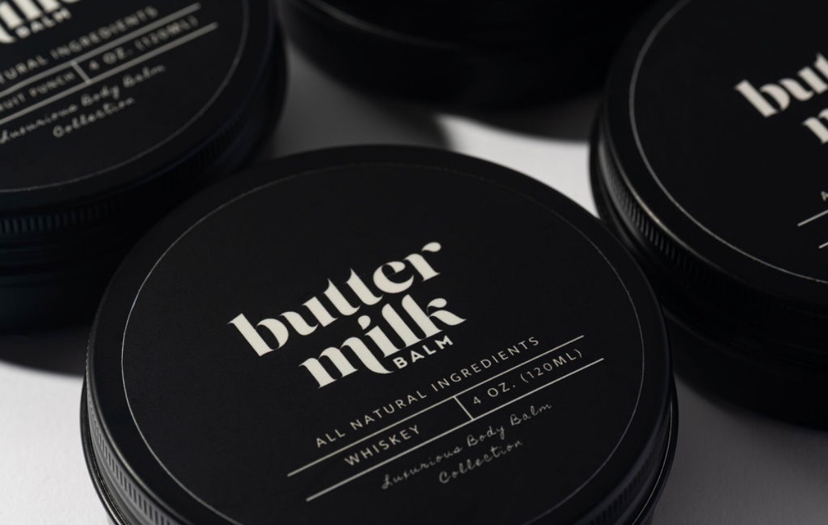 Buttermilk Balm Whiskey body balm jars arranged in editorial light