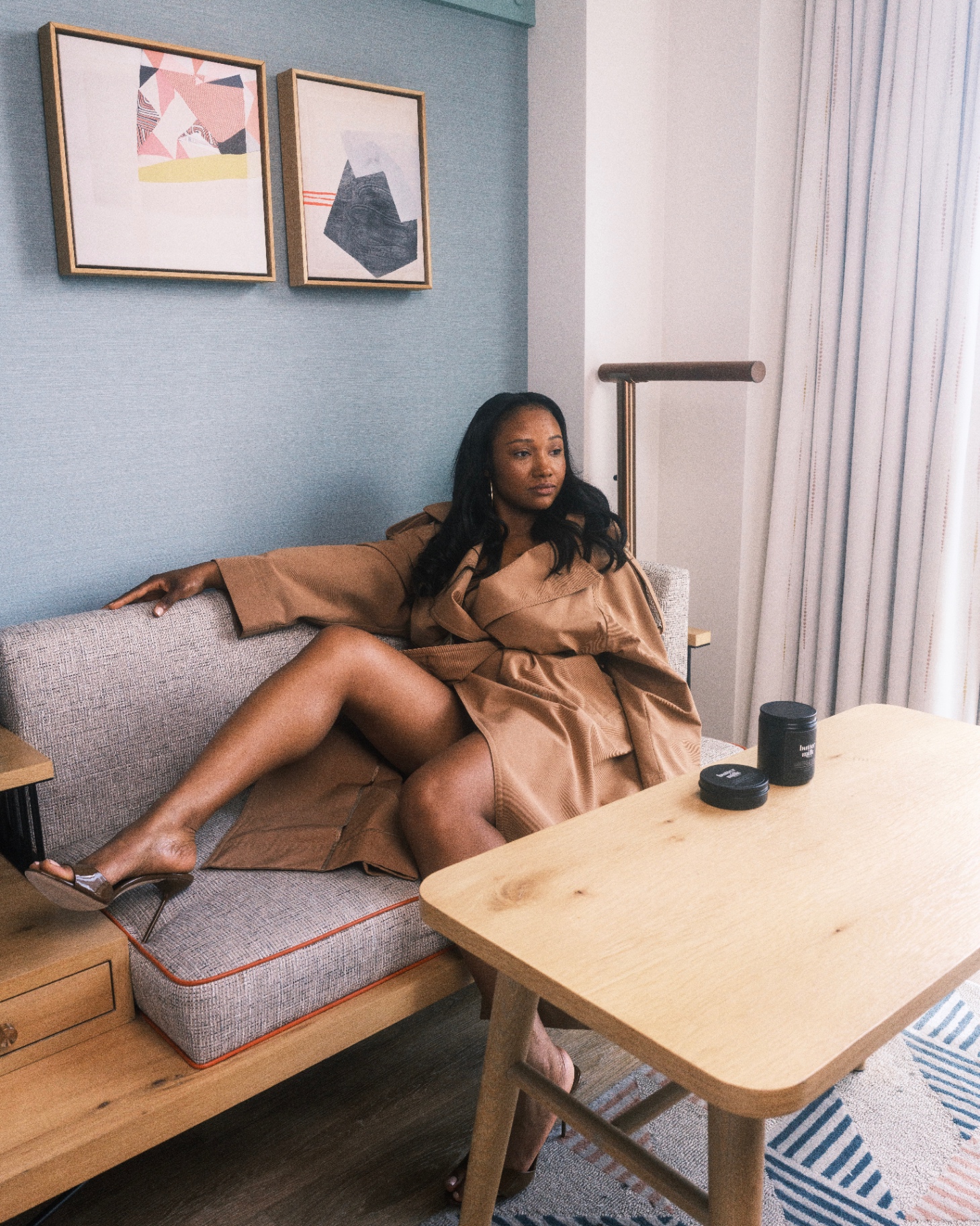 Model in trench coat with Buttermilk Balm jars on table