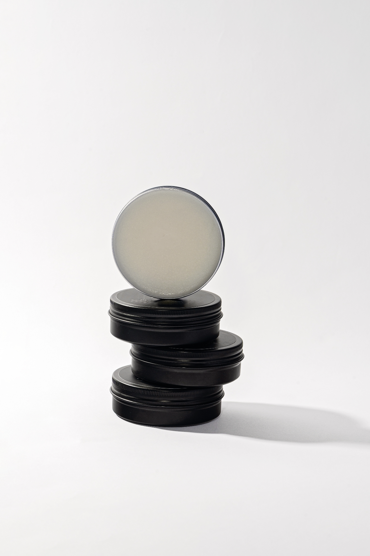 Stack of black Buttermilk Balm tins with one lid open