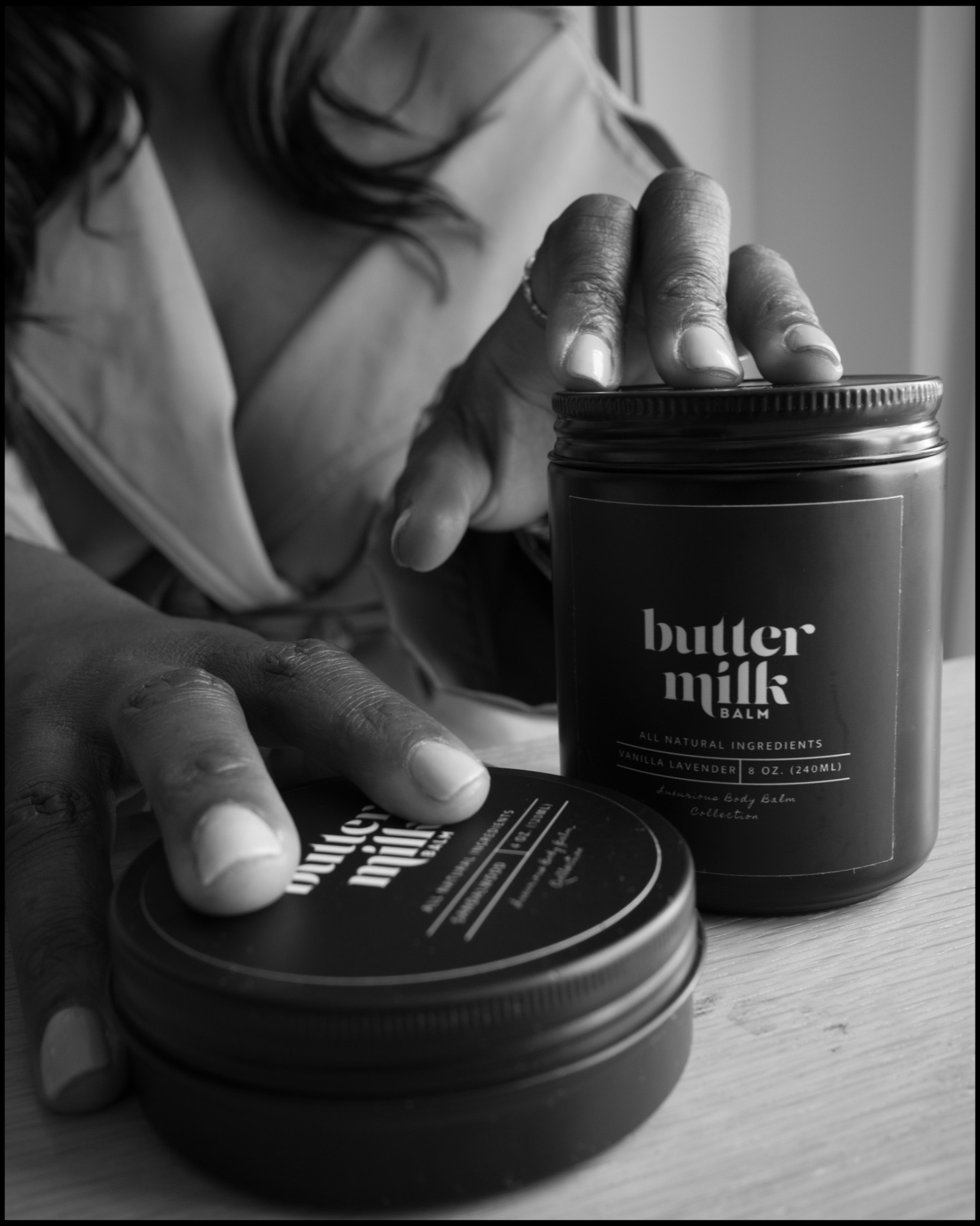 A pair of hands gently holding an amber jar of body balm in warm light